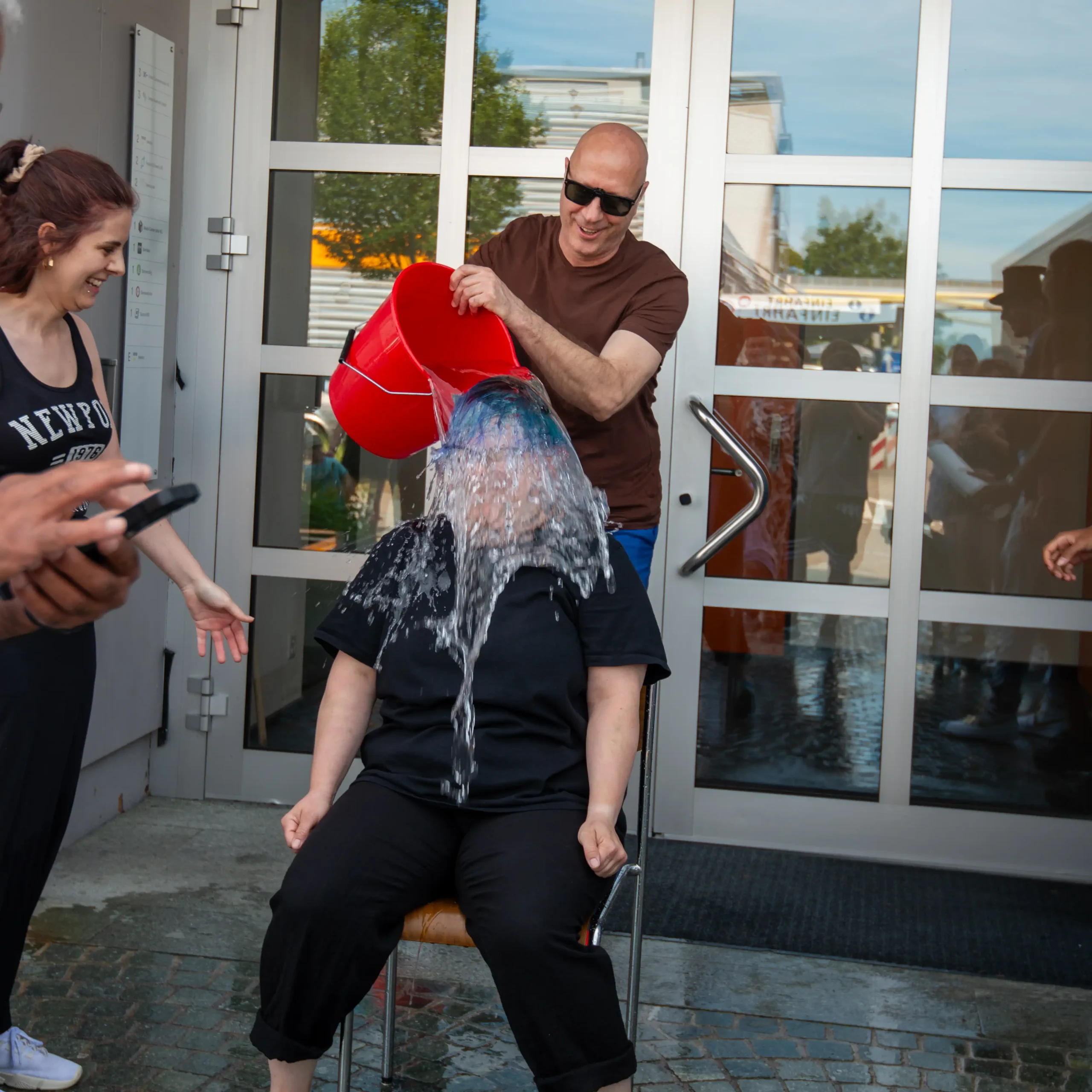 Gautschete von Laura Caprez bei der Media Center Uster. Laure bekommt vor allen Zuschauenden einen Eimer Wasser von Marcel Rieder über den Kopf geleert.