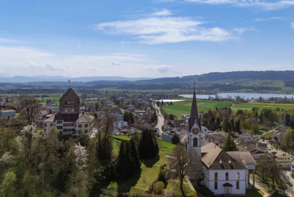 Drohnenaufnahme der Stadt Uster mit Burg und Kirche. Im Hintergrund ist der Greifensee zu sehen.